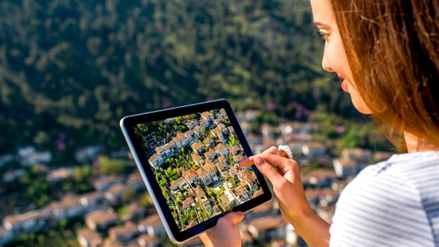 Frau schaut sich auf einem Tablet in ihrer Hand ländliche Regionen an.